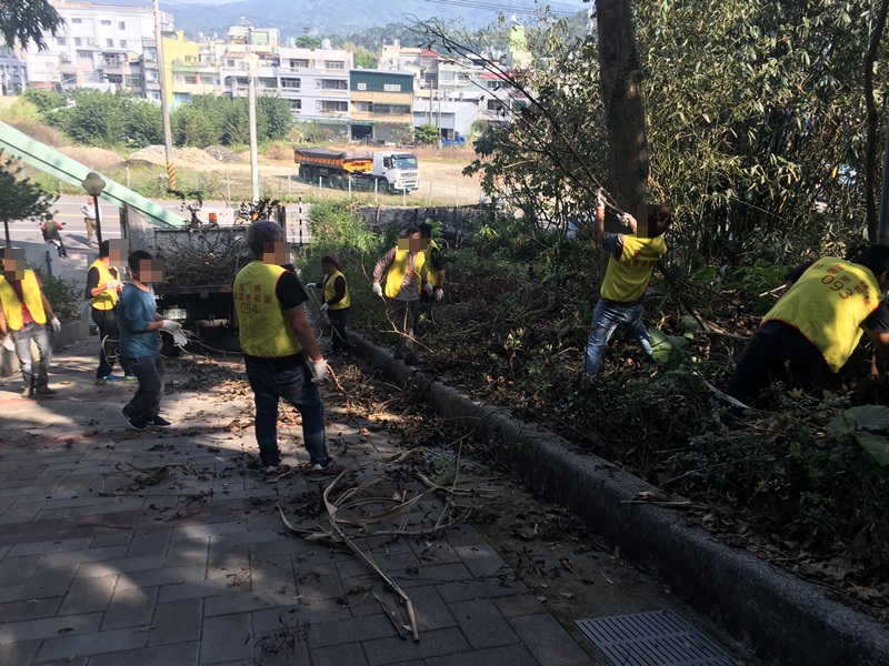05.梅山公園側門入口處走道，有許多堆積未清的枯樹枝，勞動人協助搬運上車。