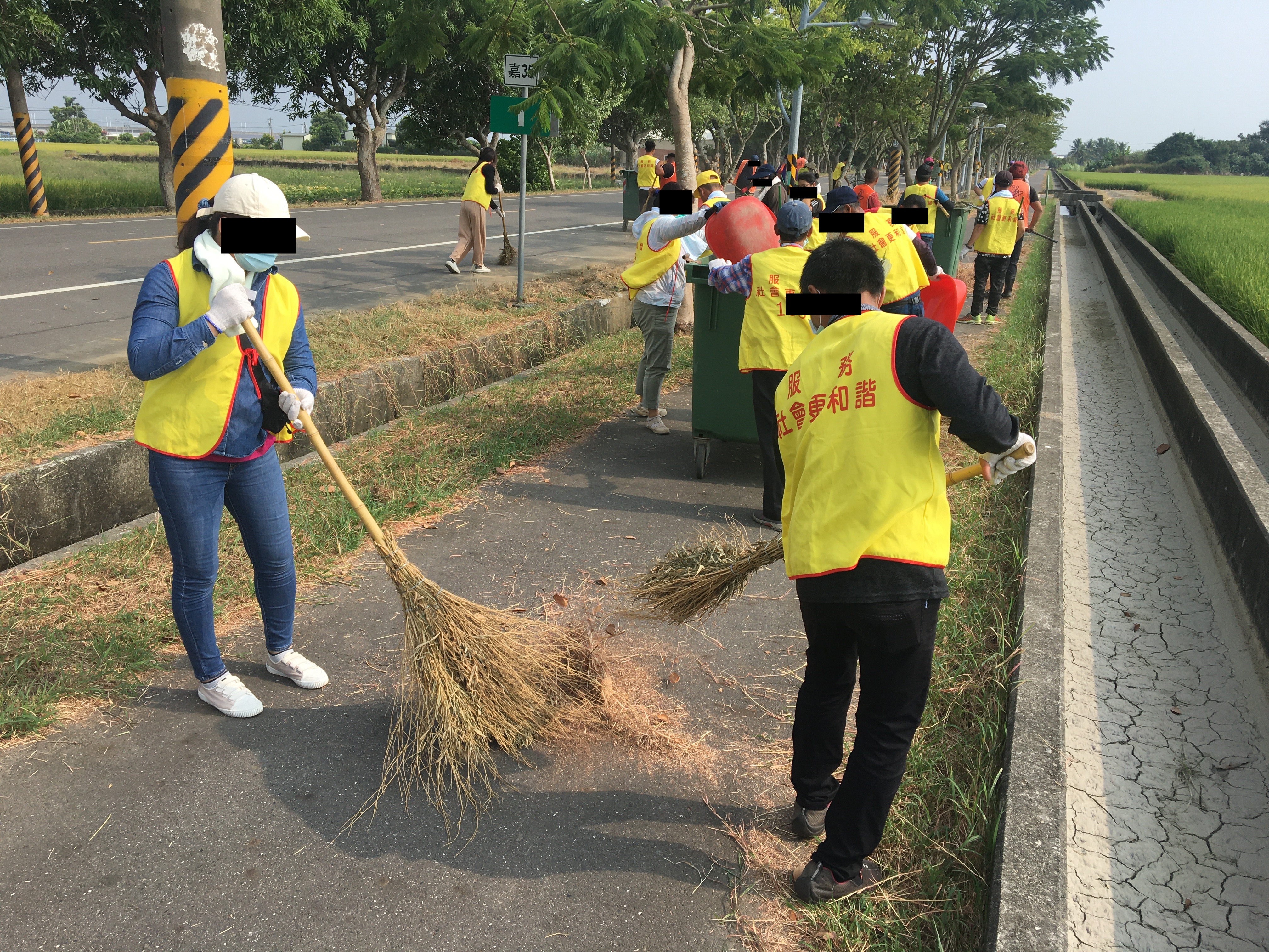07.社會勞動人用竹掃把將自行車道上落葉、雜草打掃成堆。