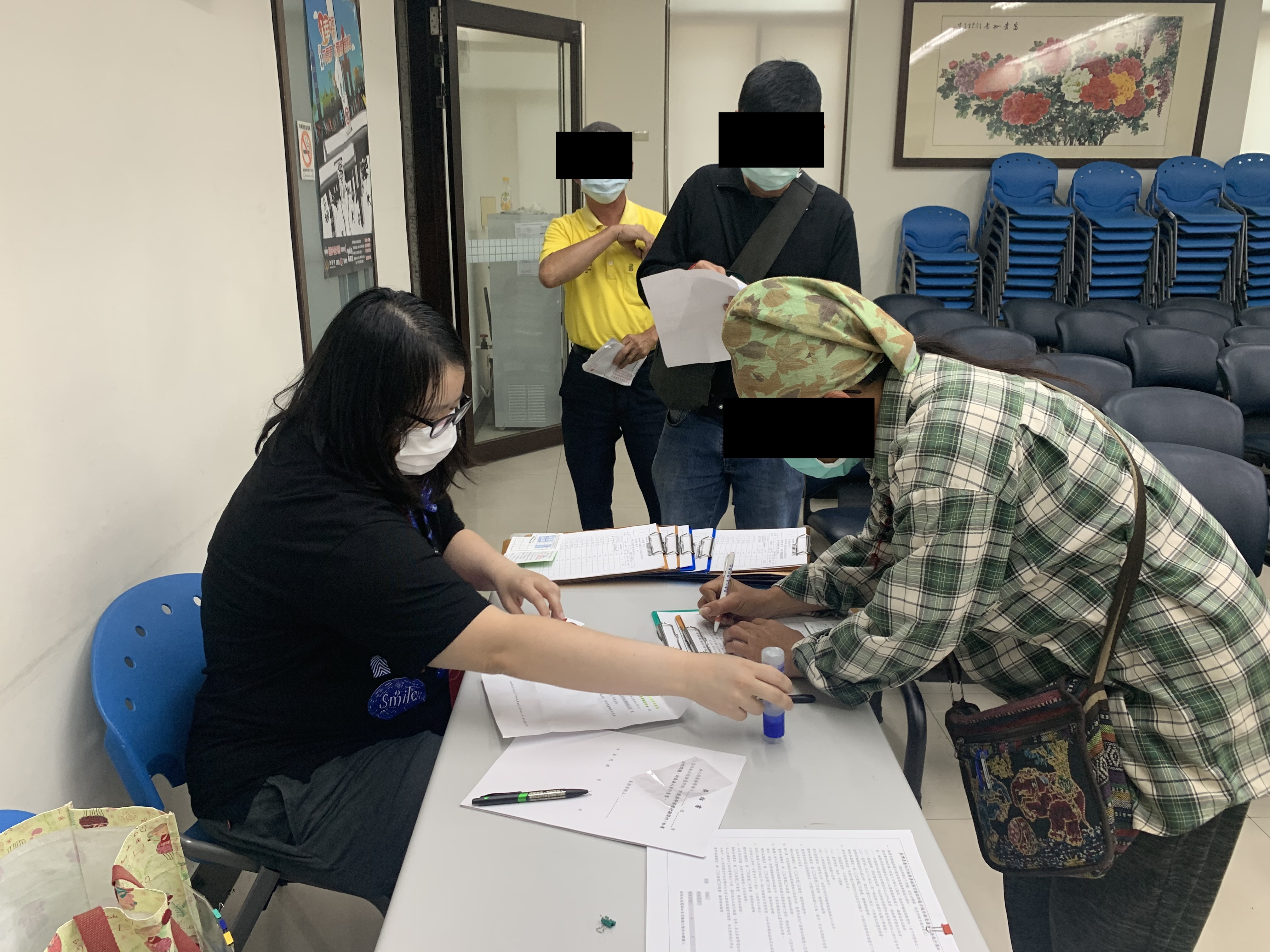 學員依序排隊等待報到，觀護佐理員細心協助相關資料之填寫。